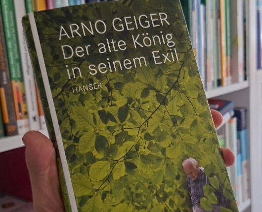 "Der alte König in seinem Exil" von Arno Geiger - das Buch vor einem Bücherregal